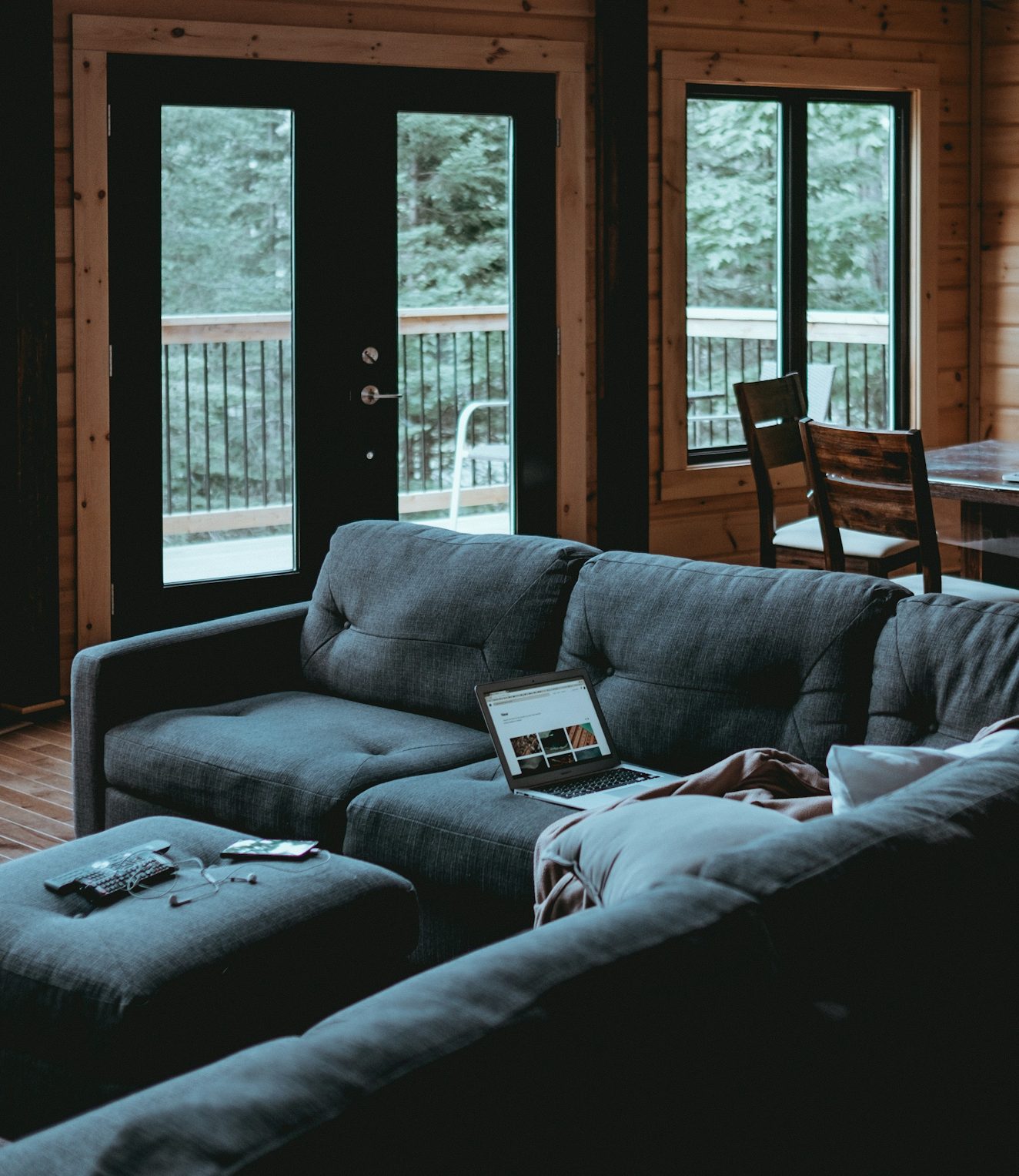 Mooie woonkamer Gezellige woonkamer met een grijze bank en grote ramen met uitzicht op de natuur.